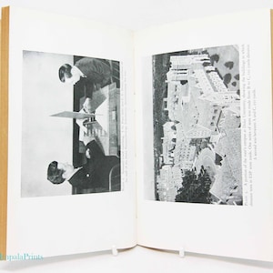 May include: Open book with black and white photographs. One photo shows two men, one looking down at a device. The other photo is an aerial view of a university campus. Text reads "A portion of the men's campus at Duke University."