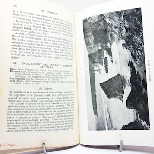 May include: Open book with text and a black and white photograph of a rock formation. The text on the left page discusses St. Cubert and the Lost Church of St. Piran. The right page features the words "Bedruthan Steps."