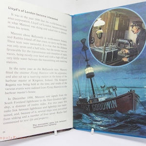 以下が含まれることがあります： テキストとイラストが掲載された開いた本。イラストの1つは、海上の「イースト・グッドウィン」と書かれた船を示しています。もう1つは、円形のフレーム内で機器を操作している男性を示しています。テキストはマルコーニの無線実験について説明しています。