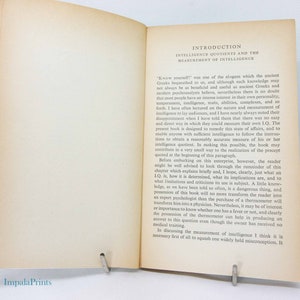 May include: Open book with text on intelligence quotients and measurement. The pages are aged with a slight yellow hue. The title "Introduction" is at the top, followed by the subtitle. A metal clip holds the pages open.