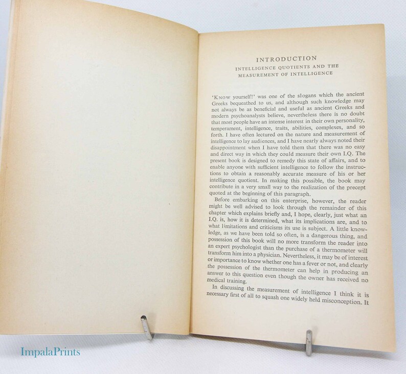 May include: Open book with text on intelligence quotients and measurement. The pages are aged with a slight yellow hue. The title "Introduction" is at the top, followed by the subtitle. A metal clip holds the pages open.