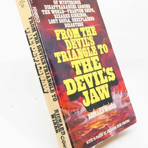 Puede incluir: Un libro de bolsillo titulado "From the Devil's Triangle to the Devil's Jaw" de Richard Winer. La portada presenta un diseño rojo y amarillo con el título en letras amarillas grandes. Publicado por Corgi, incluye 16 páginas de fotos.