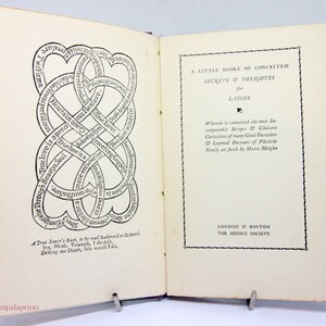 May include: An open book with a black and white illustration of a knot with text around it. The book's title page reads "A Little Booke of Conceited Secrets & Delights for Ladies" and is published by The Medici Society.