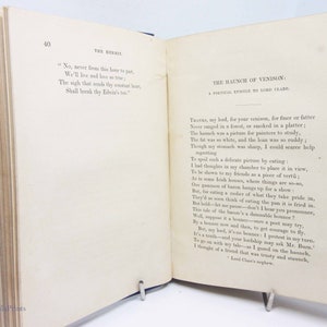 May include: A page from a vintage book with a blue cover. The page is filled with text about a haunch of venison. The text is in a traditional font and is written in a formal style. The text includes the phrase "Thanks, my lord, for your venison, for finer or fatter".