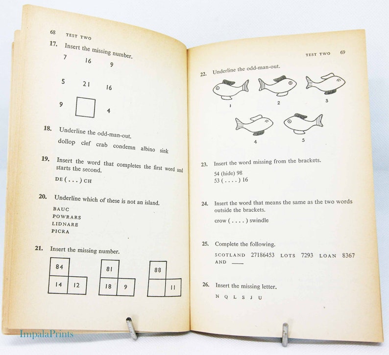 May include: Open book with printed test questions. Pages are yellowed with age. Questions include number sequences, word puzzles, and identifying the odd one out. The text "TEST TWO" is visible at the top of the pages. The Impala Prints logo is at the bottom.
