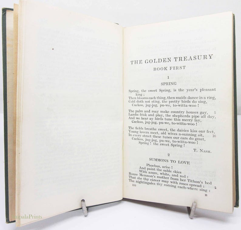 May include: An open book with the title "THE GOLDEN TREASURY BOOK FIRST" visible. The pages are aged, with black text. The book is held open by a metal clip. The text includes the poem "Spring" by T. Nash.