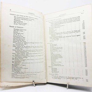 May include: An open book with a table of contents listing poems and legends of New England. The book is bound in brown leather with gold lettering on the spine. The pages are yellowed with age.
