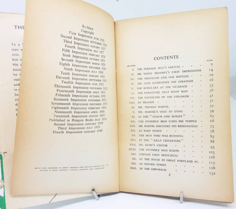Op de afbeelding: Open boek met verouderde, vergeelde pagina's. De linkerpagina toont de drukgeschiedenis van het boek, terwijl de rechterpagina de inhoudsopgave weergeeft, met hoofdstuktitels zoals "The Strange Man's Arrival".