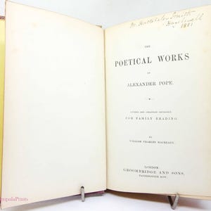 May include: An open antique book, titled "The Poetical Works of Alexander Pope." The title page is visible, with black text on aged paper. The cover is burgundy. Handwritten inscription at the top of the page.