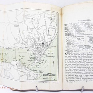 Puede incluir: Libro abierto con un mapa detallado en blanco y negro de Teignmouth, Inglaterra, y sus alrededores. El mapa incluye carreteras, edificios y características geográficas. Texto a la derecha describe la ciudad.