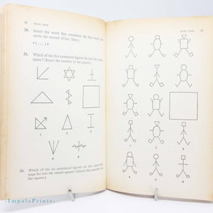 May include: Open book with vintage test questions and geometric shapes. The text reads "TEST ONE" and includes questions about completing words and matching figures. The pages are aged with a visible watermark.