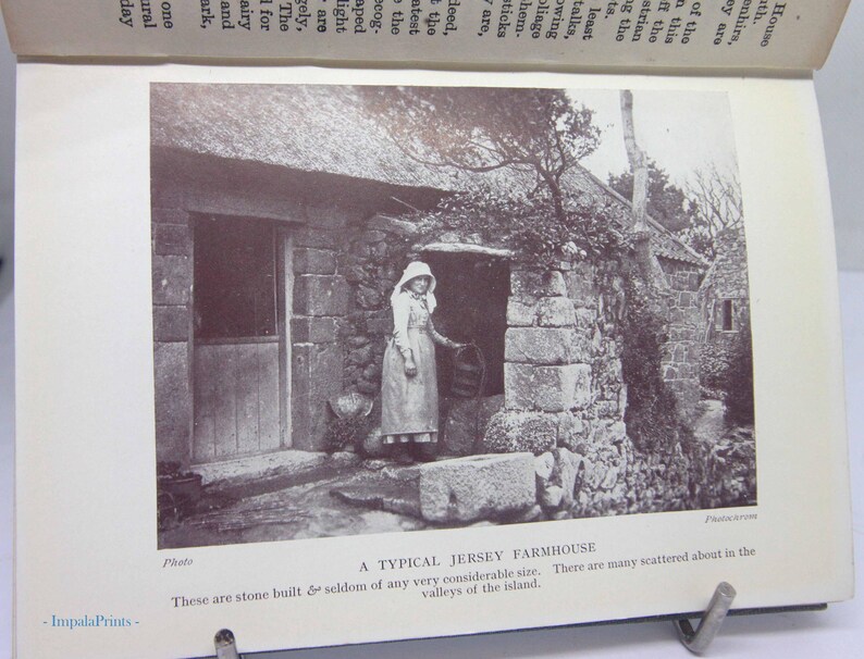 May include: A black and white photograph of a stone farmhouse with a thatched roof. A person in a long dress and bonnet stands in the doorway. The text reads "A TYPICAL JERSEY FARMHOUSE".