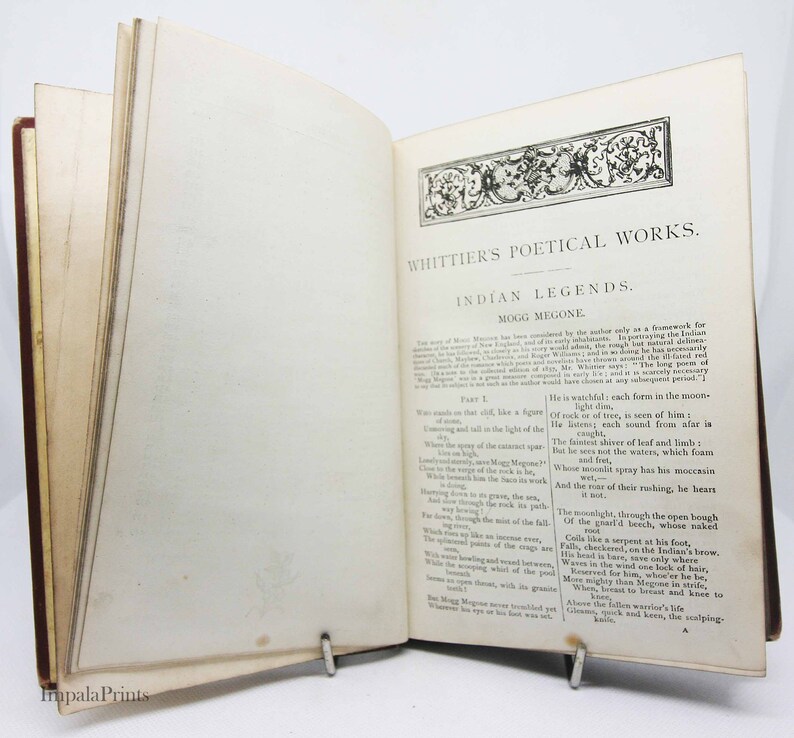 May include: An open book with a brown leather cover and yellowed pages. The text on the page reads "Whittier's Poetical Works. Indian Legends. Part I. Mogg Megone."