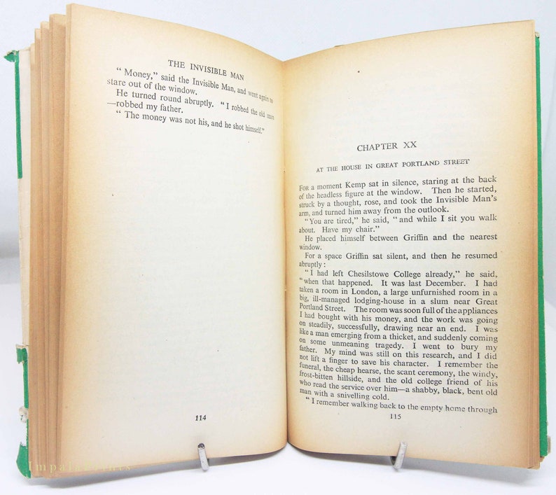 Op de afbeelding: Een open boek met verouderde, vergeelde pagina's, opengehouden door een metalen clip. De tekst op de linkerpagina luidt "THE INVISIBLE MAN" en op de rechterpagina "CHAPTER XX". Het boek heeft een groene rug.