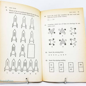 May include: Open book with black and white illustrations and text. Page 92 features a rocket-shaped puzzle with numbered figures. Page 93 includes word and number puzzles. The book is held open by a metal clip.