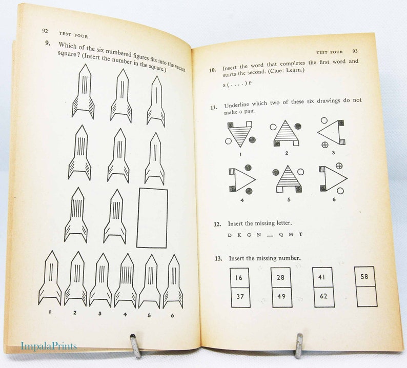 May include: Open book with black and white illustrations and text. Page 92 features a rocket-shaped puzzle with numbered figures. Page 93 includes word and number puzzles. The book is held open by a metal clip.