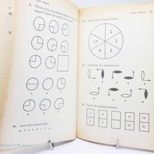 May include: Open book with pages featuring math and logic puzzles. The left page has questions about shapes and missing letters. The right page includes number sequences and an odd-one-out exercise. The text "TEST THREE" is visible at the top of the pages.