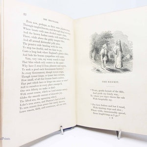 May include: An open book with a black and white illustration of a man and a hermit in a forest setting. The book has text on the pages, including the title "The Hermit".