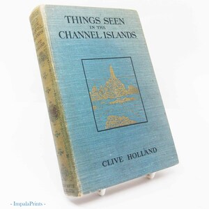 May include: A vintage book titled "Things Seen in the Channel Islands" by Clive Holland. The book has a light blue cover with gold lettering and a gold illustration. The spine is a faded gold color.