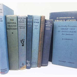 May include: A collection of vintage books in various shades of blue, green, and brown. Titles include "Calypso Islands," "The Russell English Dictionary," and "Little Women." The books are arranged vertically, with visible text on the spines.