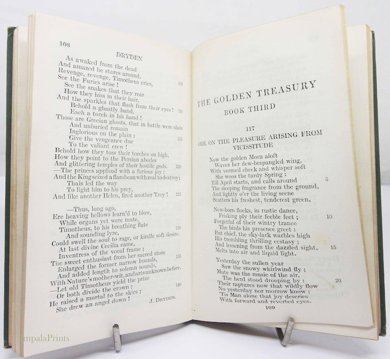 May include: An open book with a green cover, featuring text from "The Golden Treasury, Book Third." The pages display poetry by Dryden. A metal book stand holds the book open.