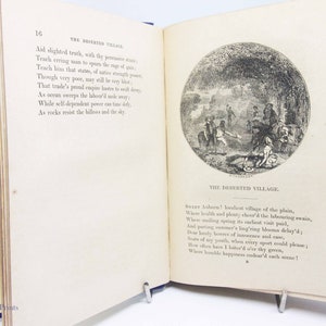 May include: An illustration from a vintage book depicting a rural village scene. The image shows a group of people gathered in a field, with a small village in the background. The text "The Deserted Village" is printed below the image.