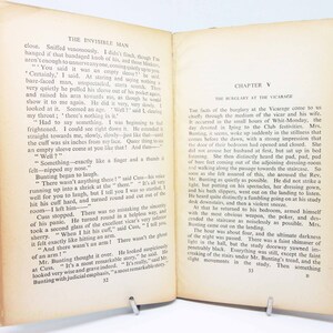 Op de afbeelding: Open boek met tekst uit "The Invisible Man" en "Hoofdstuk V: De inbraak in de pastorie." De pagina's zijn vergeeld. Het boek is open op pagina's 32 en 33, met een groene rug.