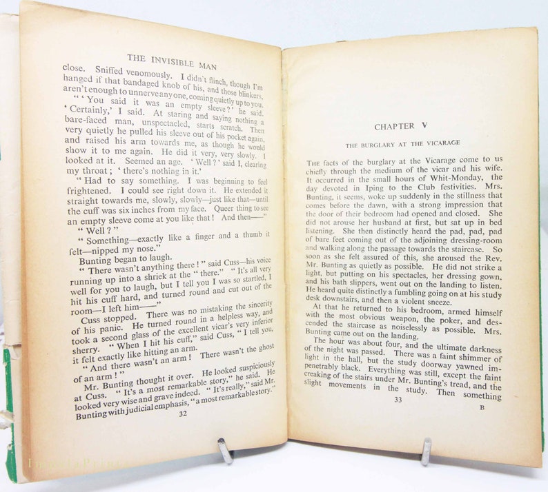Op de afbeelding: Open boek met tekst uit "The Invisible Man" en "Hoofdstuk V: De inbraak in de pastorie." De pagina's zijn vergeeld. Het boek is open op pagina's 32 en 33, met een groene rug.