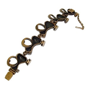 May include: A bronze bracelet with a chain closure. The bracelet is made up of a series of linked, heart-shaped pieces.