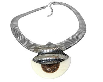 May include: A silver chain necklace with a large, white, shell-shaped pendant. The pendant has a copper-colored center.