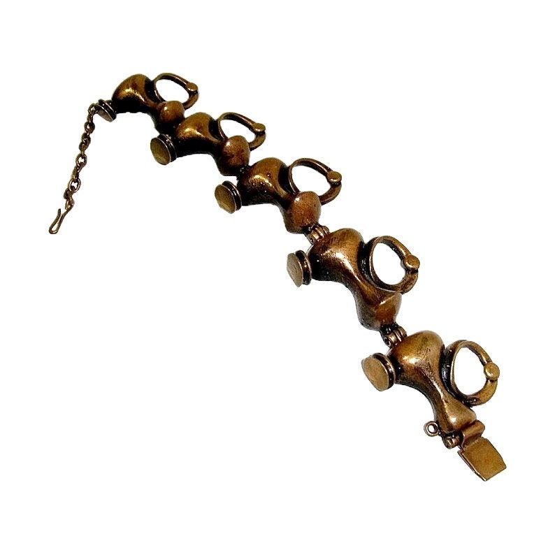 May include: A bronze bracelet with a chain and a series of connected, stylized,  elongated,  teardrop-shaped links.