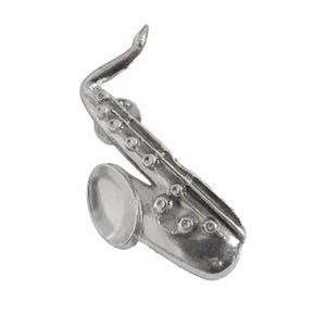 May include: A silver saxophone pin, a detailed miniature replica of a musical instrument.