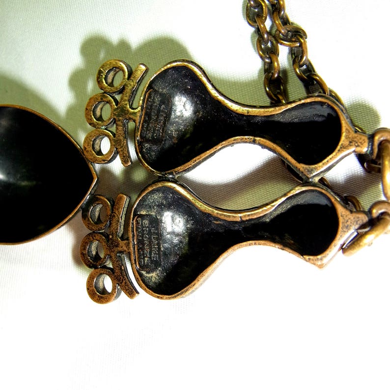 May include: A gold-tone necklace with a pendant featuring two stylized figures. The pendant is marked "L. Dalize, France".