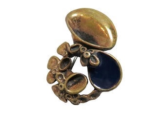 May include: A gold-toned brooch with a blue enamel accent. The brooch features a cluster of small, round shapes and a larger, oval shape.