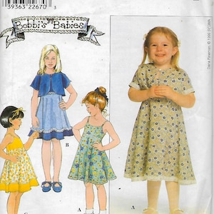 May include: A sewing pattern for three girls' dresses. The pattern is called "Bobbi's Babies" and is from Simplicity. The dresses are all different styles, one with a cardigan, one with straps, and one with a button-up front.