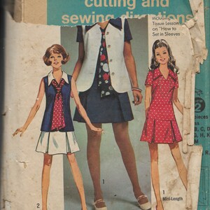 May include: Vintage Simplicity 8615 sewing pattern featuring three retro outfits. The pattern includes a mini-length dress with white polka dots, a navy blue vest with a white blouse, and a navy blue dress with a white skirt. The pattern includes instructions on how to set in sleeves.