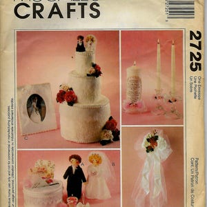 May include: A wedding themed craft pattern featuring a three-tiered cake, a bride and groom doll, a tissue box cover, and a candle holder. The pattern is titled "2725 One Envelope, Une Pochette, Un Sobre".