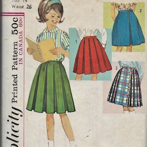 Puede incluir: Patrón de costura Simplicity número 5123 para una falda de niña. El patrón incluye instrucciones para hacer tres estilos diferentes de faldas: una falda de cuadros verdes, una falda roja y una falda azul. El patrón es para la talla 14 con una cintura de 66 cm.