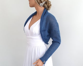 May include: A blue knitted shrug with long sleeves. The shrug is made of a soft, lightweight fabric and is perfect for adding a touch of warmth and style to any outfit.