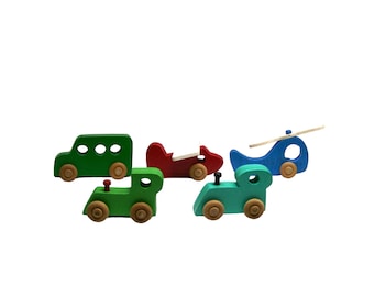 May include: Five wooden toy vehicles, including a green bus, a red airplane, a blue helicopter, and two green cars. The toys have wooden wheels and are painted in bright colors.