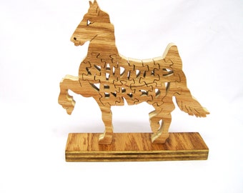 May include: A wooden horse puzzle with intricate cutouts, standing on a wooden base. The horse is in a rearing pose with its front leg raised.