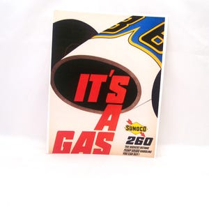 May include: A vintage Sunoco gas advertisement featuring the text "IT'S A GAS" in red, with a stylized image of a gas pump nozzle. The ad includes the Sunoco logo and "260" with the tagline "THE HIGHEST OCTANE PUMP GRADE GASOLINE YOU CAN BUY!"