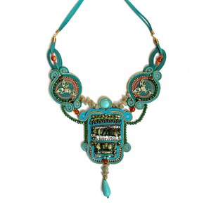 May include: A turquoise and green beaded necklace with a large pendant featuring a geometric design. The pendant is adorned with turquoise, green, and gold beads.
