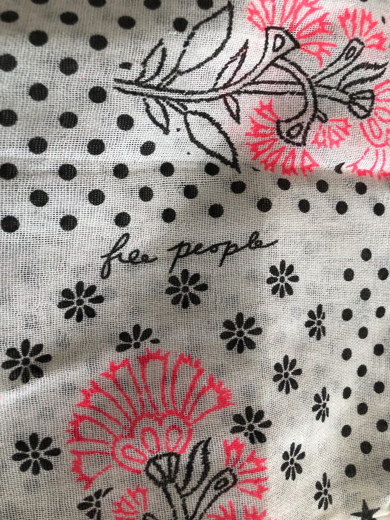 Puede incluir: Tela blanca con lunares negros y dise&ntilde;os florales en negro y rosa ne&oacute;n. Las palabras "free people" est&aacute;n escritas en cursiva. La tela tiene un aspecto ligero y transparente.