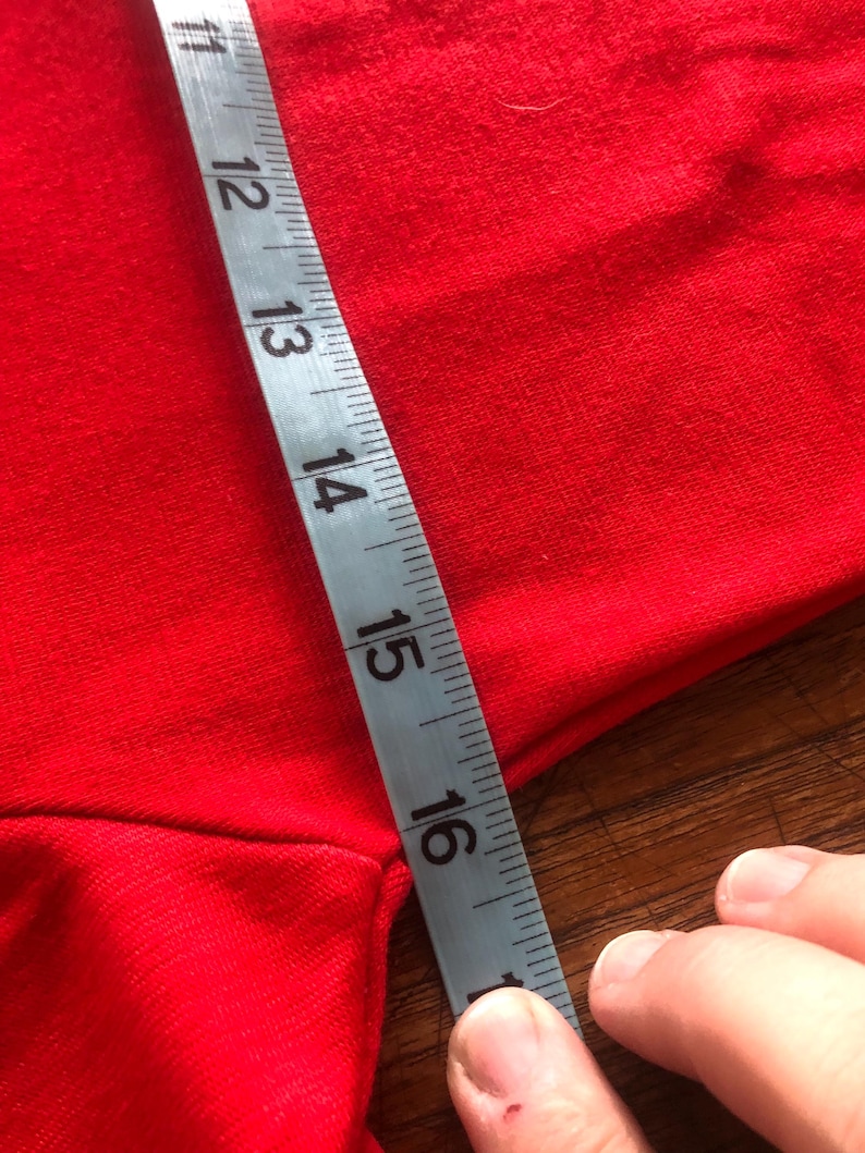 Peut inclure: Un tissu rouge est mesur&eacute; avec un ruban &agrave; mesurer argent&eacute;. Le ruban indique une mesure de 28 &agrave; 40 cm. Le tissu est de couleur rouge vif et uni.