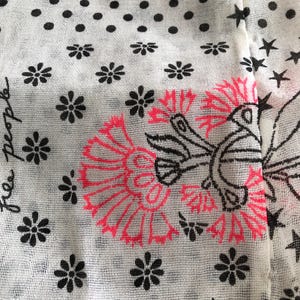 Puede incluir: Primer plano de una tela blanca con un patr&oacute;n repetido de lunares negros, flores y estrellas. Se presenta un gran dise&ntilde;o floral en negro y rosa ne&oacute;n. La palabra "people" est&aacute; escrita en cursiva.