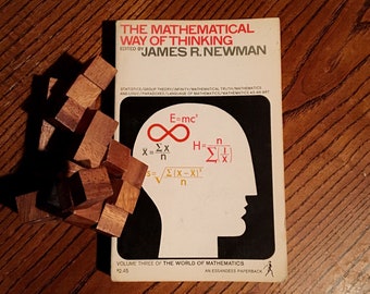 Könnte beinhalten: Ein Buch mit dem Titel "The Mathematical Way of Thinking", herausgegeben von James R. Newman. Der Umschlag zeigt eine weiße Silhouette eines Kopfes mit mathematischen Formeln darin. Das Buch ist Teil der Reihe "The World of Mathematics".