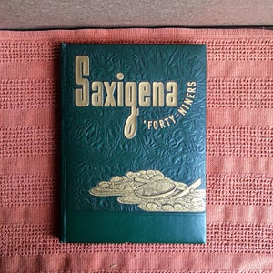 May include: A green leather-bound book with gold lettering that reads "Saxigena 'Forty-Niners". The cover features a gold illustration of a pan and a shovel.