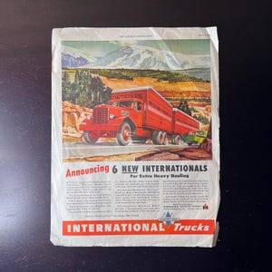 Puede incluir: Anuncio publicitario vintage de International Trucks. La imagen presenta un camión rojo con dos remolques, etiquetados como "Western", en una carretera con montañas al fondo. El texto anuncia "6 NUEVOS INTERNATIONALS para transporte pesado".
