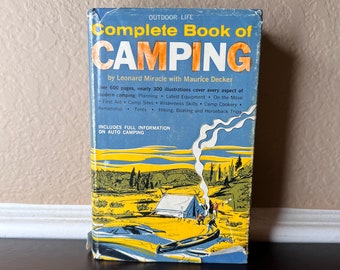 May include: A vintage book titled "Complete Book of Camping" with a blue cover and colorful illustrations of camping scenes. The book includes information on planning, equipment, and wilderness skills. The cover text reads "Outdoor Life" and "Includes Full Information on Auto Camping."